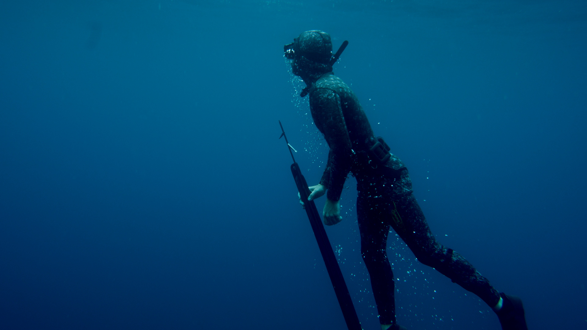 Freediver ascending through deep blue water