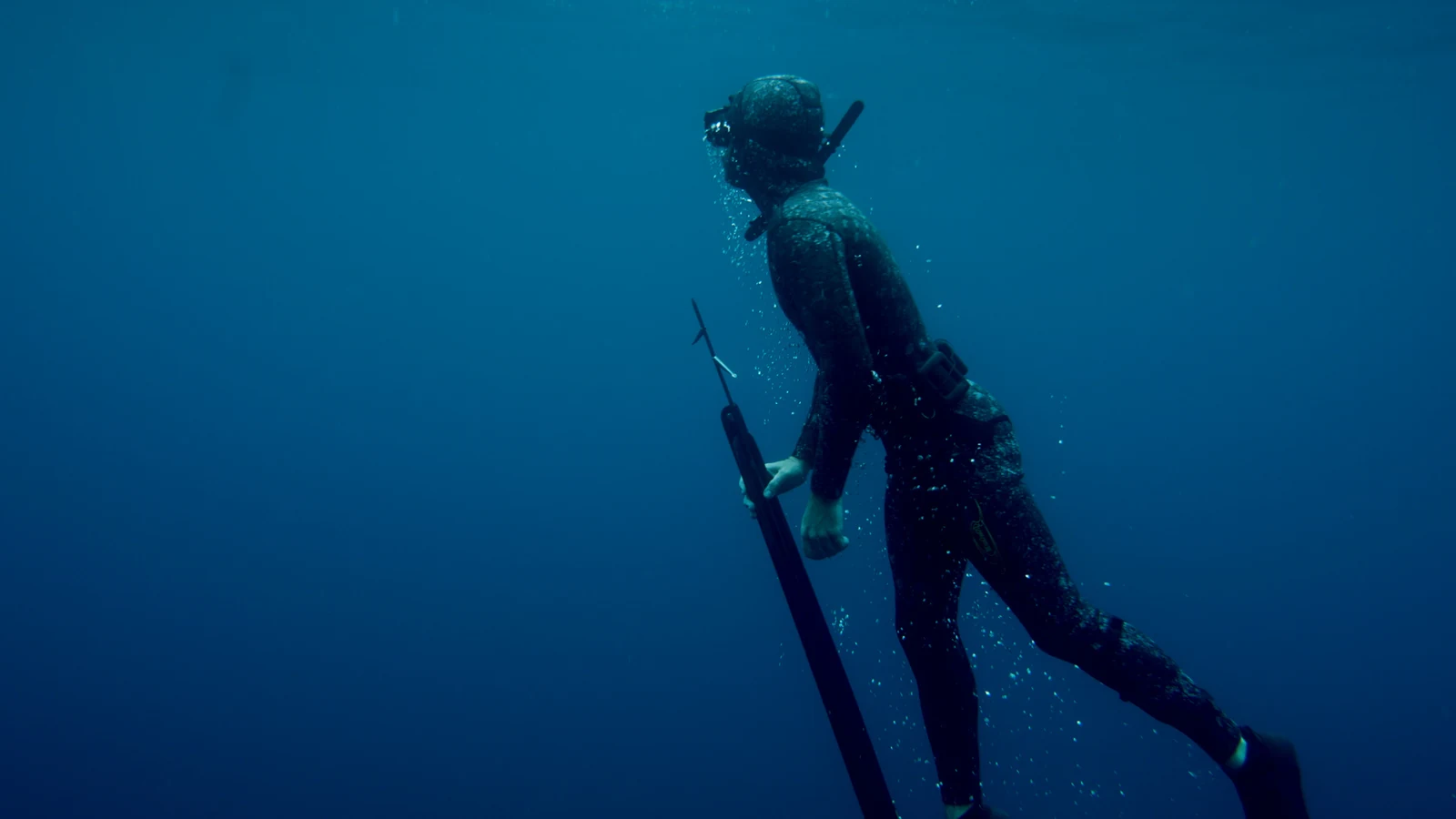 Freediver ascending through deep blue water